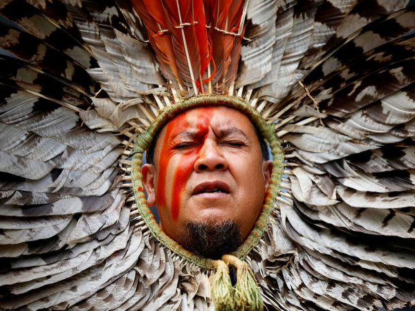 Un uomo indigeno canta davanti al tribunale di Parigi per protestare contro l'attività della multinazionale Casino in Amazzonia