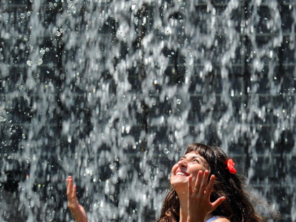 Una ragazza si rinfresca nella fontana "Le quattro stagioni" all'interno del parco Valentino, a Torino