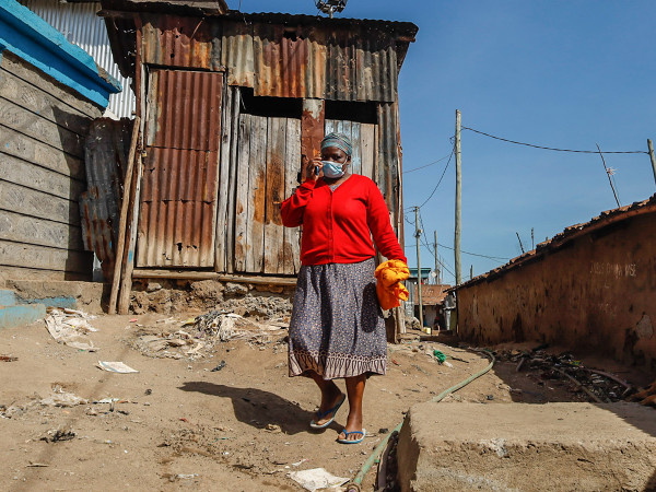 Una donna passa davanti al quartiere locale di Kibera Slums, a Nairobi, dove l'estrema felicità della comunità sorprende visto l'alto tasso di povertà e la mancanza di lavoro.