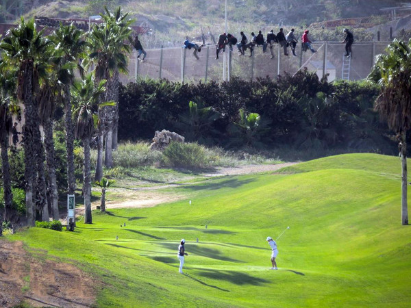 Nello scatto di José Palazón tratto dal profilo twitter dell'organizzazione umanitaria Prodein, il contrasto di una città di frontiera come Melilla. Sulla rete che circonda la città sono rimasti in bilico, per più di 12 ore, circa settanta migranti che hanno cercato di superare la barriera. A pochi passi dalla loro disperazione, gli abitanti di Melilla hanno continuato a giocare sui campi da golf