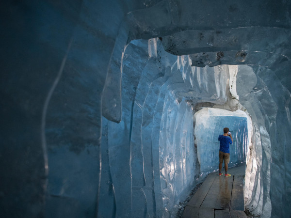 Un visitatore esplora una grotta di ghiaccio del ghiacciaio alpino del Rodano, all'estremità nord-est del Canton Vallese in Svizzera. Si tratta Si tratta del più antico delle Alpi: oggi è protetto da speciali coperte bianche per scongiurarne lo scioglimento