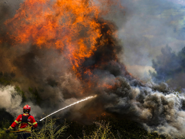 Un vigile del fuoco combatte le fiamme che circondano il villaggio di Ancede durante un incendio nel comune di Baiao, nel nord del Portogallo, il 15 luglio 2022.