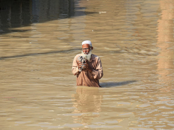 Un uomo attraversa un'area allagata in seguito alle forti piogge nel distretto di Nowshera, nella provincia di Khyber Pakhtunkhwa, in Pakistan.