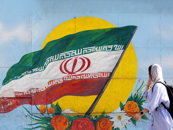 Una donna passa davanti a un graffito raffigurante la bandiera nazionale iraniana a Teheran, Iran, 09 novembre 2022. I leader iraniani hanno condannato le proteste e accusato gli Stati Uniti e Israele di aver pianificato la rivolta.