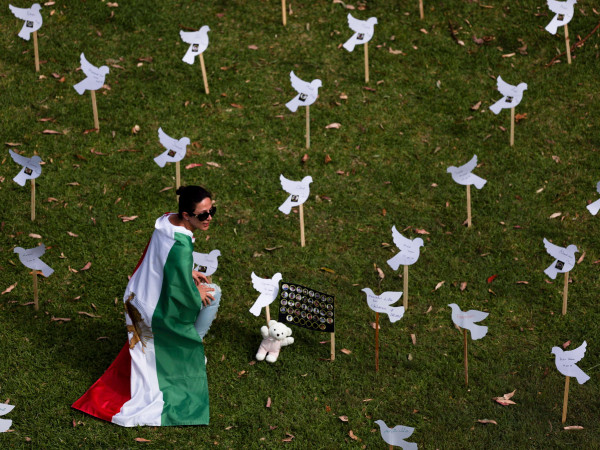 Sydney (Australia). Una manifestante indossa la bandiera iraniana tra le colombe di carta al Bicentennial Park durante una manifestazione per chiedere solidarietà ai cittadini dell'Iran.