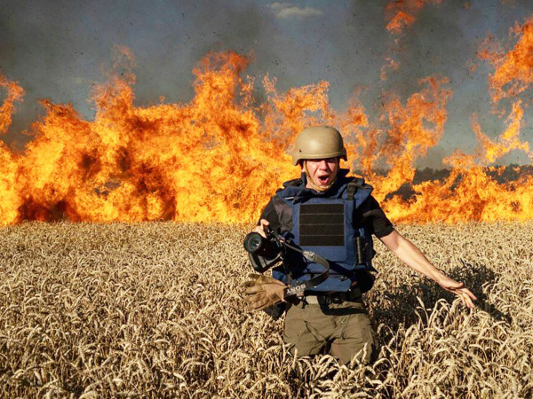 Il fotoreporter Evgeniy Maloletka fugge da un incendio in un campo di grano in fiamme nel luglio 2022, nella regione di Kharkiv