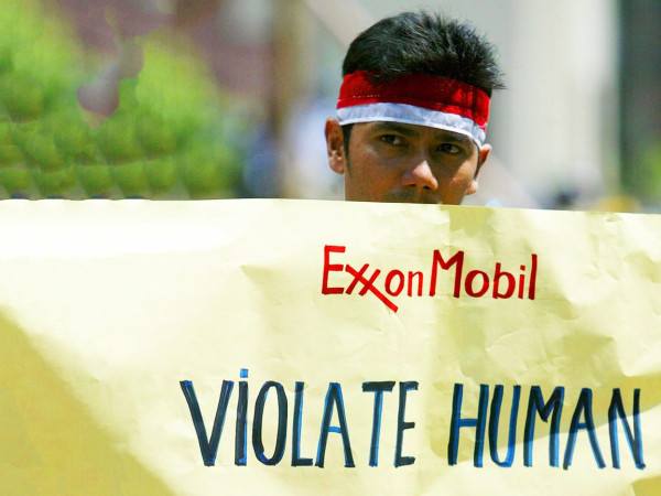 Un ex dipendente della ExxonMobil tiene un cartello durante una protesta a Giacarta, in Indonesia, il 22 novembre 2007. L'azienda è uno dei maggiori operatori di giacimenti di gas del Paese.
