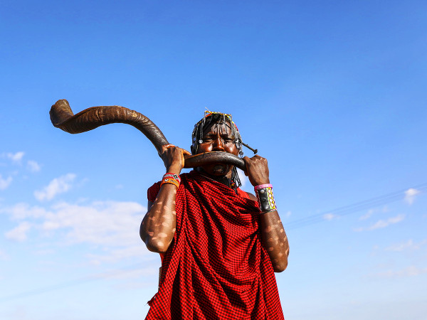 Sekenani (Kenya) Un membro della comunità Maasai in abiti tradizionali suona il corno al Festival Culturale Maasai nella Riserva Nazionale Mara. Il Festival promuove il turismo, lo scambio culturale e la pace attraverso musica, cibo, manufatti, sport tradizionali come il lancio della lancia e racconti popolari.