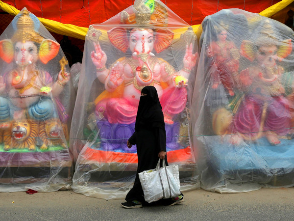 Bangalore, India. Una donna musulmana passa davanti alle statue con la testa a forma di elefante del dio indù Ganesha, prima del festival di Ganesha Chaturthi, che celebra la nascita della divinità.