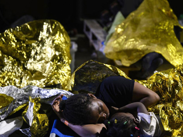Una donna e un bambino dormono fuori dal centro di accoglienza di Lampedusa, settembre 2023