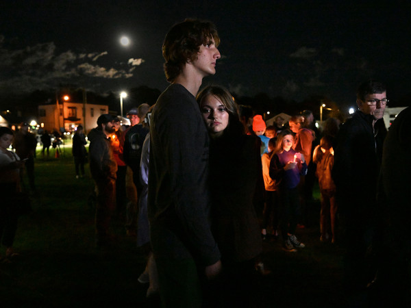 Due giovani si abbracciano durante una veglia del 28 ottobre 2023, mentre i membri della comunit&agrave; si riuniscono dopo la tragica sparatoria di massa di Lewiston