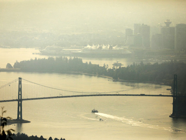 A boat passes under the Lions Gate bridge to enter Vancouver Harbour, shrouded in a haze of wildfire smoke, as seen from Cypress Mountain in North Vancouver, British Columbia, Canada, August 21, 2023