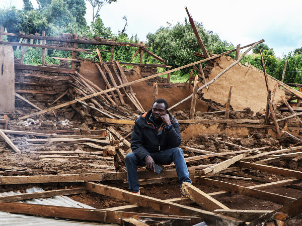 A man is seated amidst the debris of his destroyed home in Sasimwani, within the Mau Forest area.