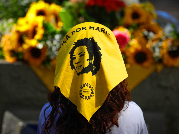 Una ragazza indossa una bandana con la frase "Giustizia per Marielle" davanti ai fiori posti ai piedi della statua della consigliera Marielle Franco, durante una manifestazione in suo onore a Rio de Janeiro, in Brasile, il 27 luglio 2023.
