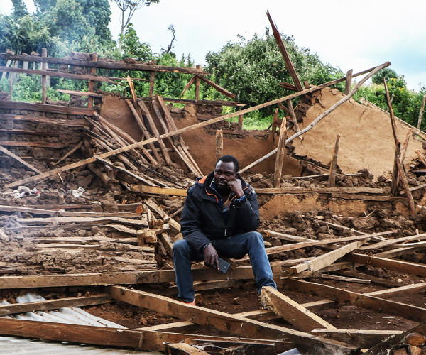 A man is seated amidst the debris of his destroyed home in Sasimwani, within the Mau Forest area.