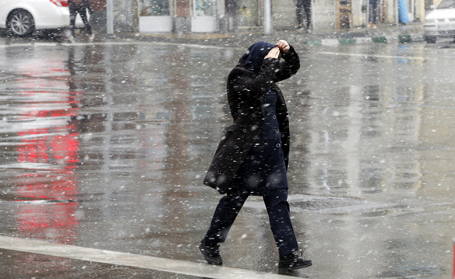 Teheran, Iran. Una donna si protegge il capo durante una eccezionale nevicata nella Capitale (EPA/ABEDIN TAHERKENAREH)