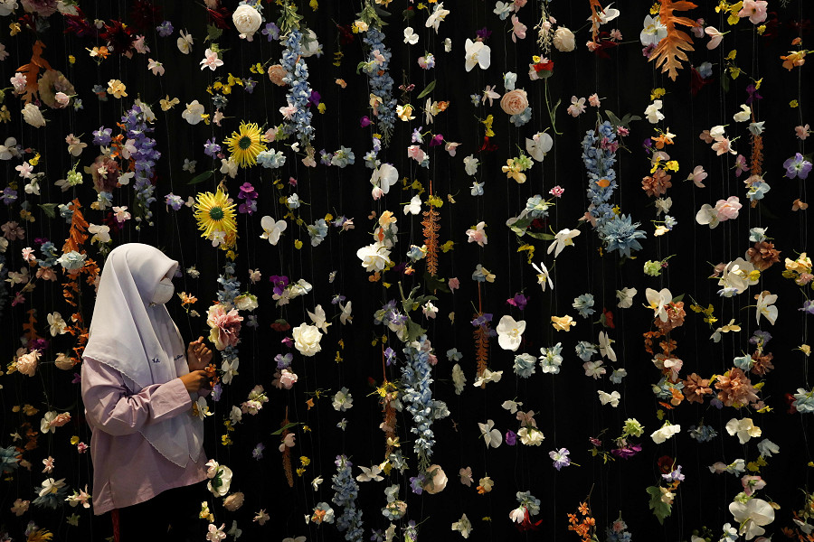 Bangkok (Thailandia). Una studentessa musulmana thailandese osserva un’installazione artistica floreale al Sustainability Expo 2022, ospitato per supportare gli obiettivi di sviluppo sostenibile del Paese da raggiungere entro il 2030, con centinaia di aziende internazionali e nazionali che espongono i loro progetti e prodotti.  