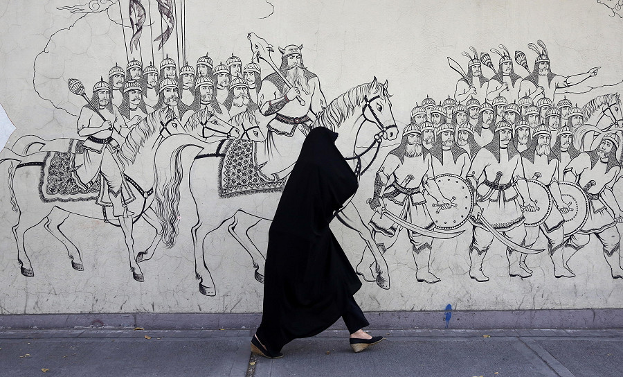 Teheran (Iran). Una donna iraniana cammina davanti a un murale in una strada della capitale. In Iran continuano le proteste scoppiate dopo la morte della 22enne Masha Amini. I leader iraniani hanno condannato i “disordini” e hanno accusato Stati Uniti e Israele di averle pianificate all’interno del Paese. 