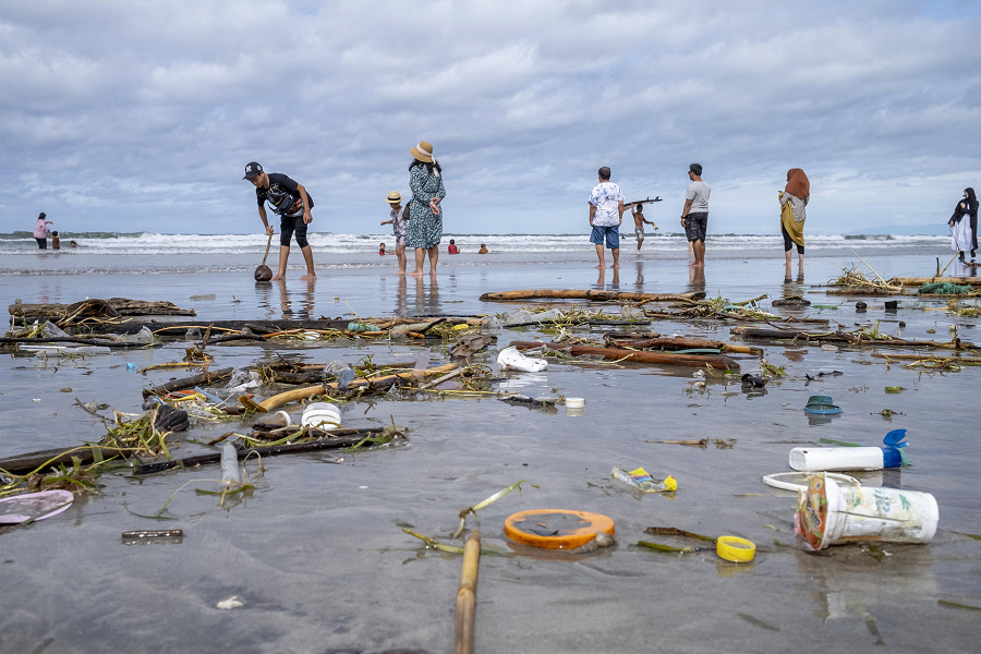 Kuta (Bali). I turisti camminano tra detriti e rifiuti di plastica nella spiaggia a sud dell’isola indonesiana. La maggior parte dei rifiuti finisce in mare in ogni stagione delle piogge a causa della mancanza di un sistema centralizzato di gestione dei rifiuti.