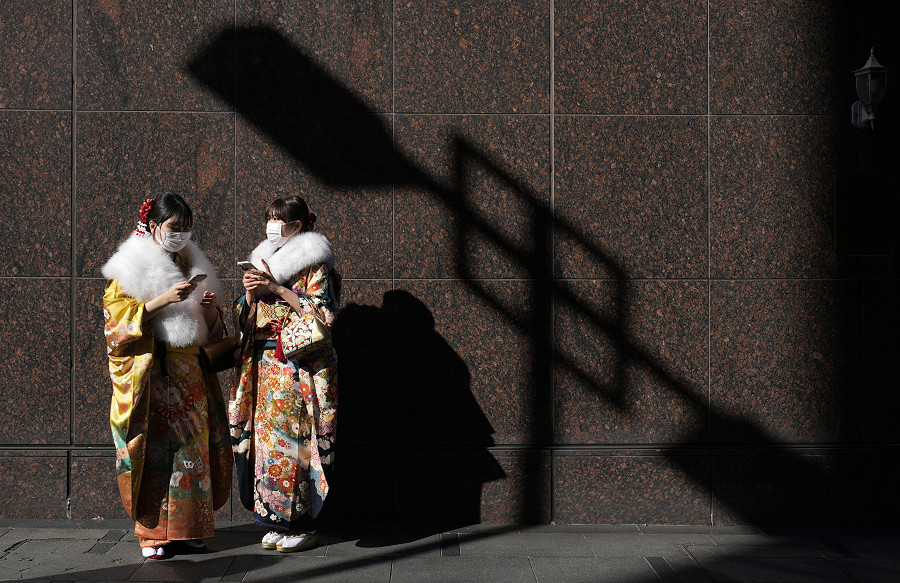 Yokohama (Giappone). Due giovani donne giapponesi in kimono munite di mascherina protettiva si trovano a poca distanza dal luogo in cui si svolge il Coming of Age Day, che si tiene a sud di Tokyo. La cerimonia celebra coloro che hanno raggiunto la maggiore et&agrave;: 20 anni. 