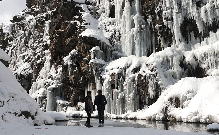 Tangmarg (India). Una coppia di turisti indiani posa vicino a una cascata ghiacciata a nord di Srinagar, la capitale estiva del Kashmir indiano. Con l’abbassamento delle temperature, la stazione sciistica di Gulmarg ha raggiunto una minima di - 12&deg;C, registrando la notte pi&ugrave; fredda mai rilevata nella regione. 
