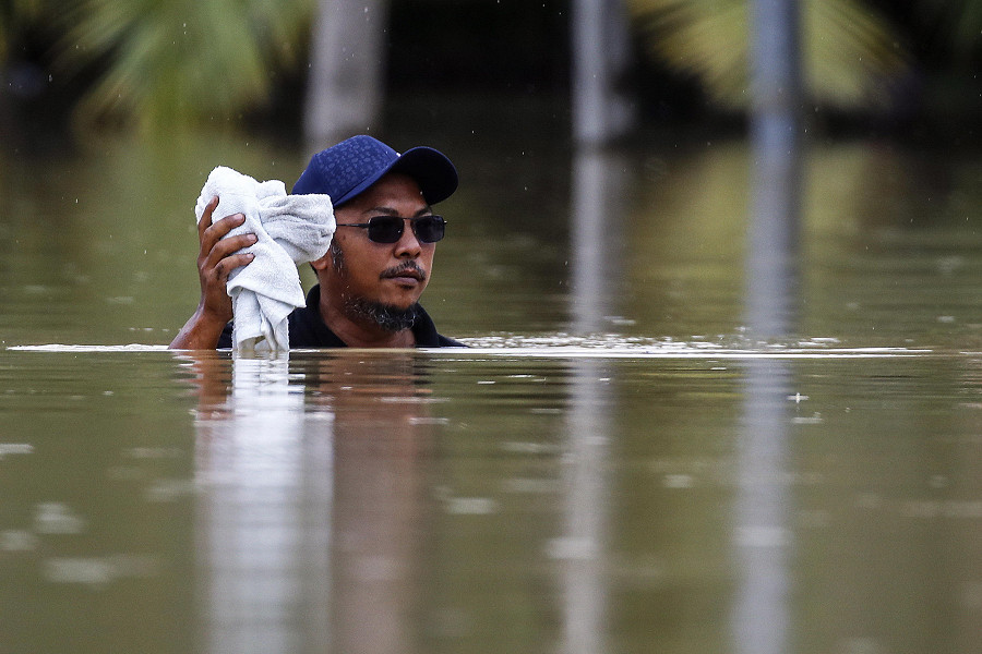 Yong Peng, Johor (Malesia). Un uomo, immerso nell’acqua fino quasi al collo, osserva la zona attorno a lui, completamente allagata, mentre continua a piovere. Secondo i media statali, sono pi&ugrave; di 33.000 le persone evacuate in 4 Stati colpiti dalle inondazioni (&copy; EPA/FAZRY ISMAIL)