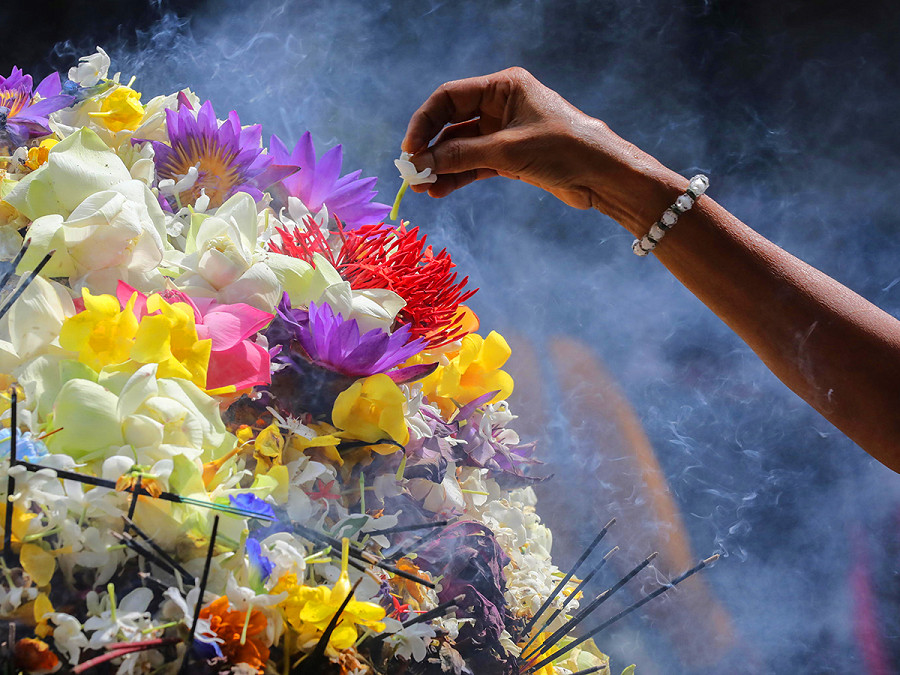 Colombo (Sri Lanka). Qualcuno offre un fiore durante una cerimonia religiosa in un tempio a Kelaniya, un sobborgo della capitale, durante un giorno di luna piena. Si tratta di occasioni sacre per i devoti del buddismo, religione ufficiale della nazione insulare dell’Asia meridionale. 