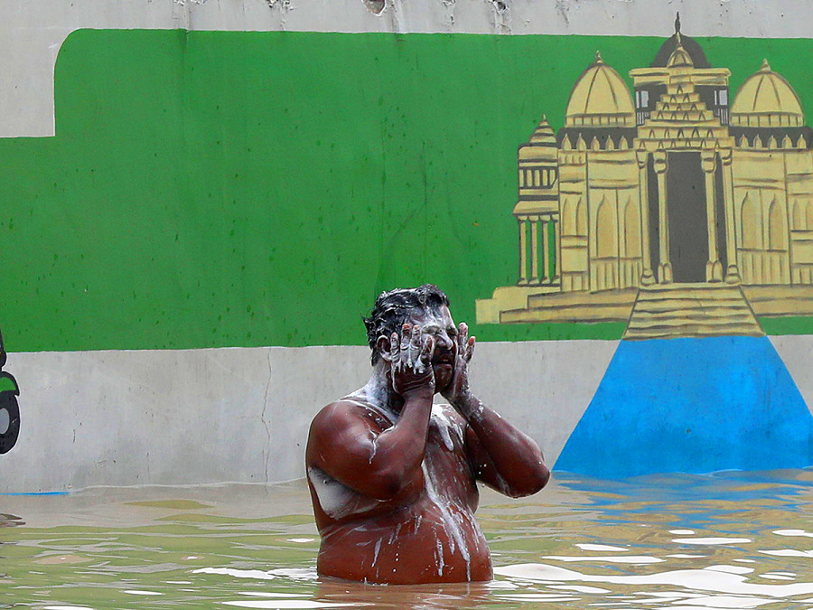 Nuova Delhi (India). Un uomo fa il bagno su una strada allagata dopo che l’acqua del fiume Yamuna ha raggiunto le strade della capitale. Il Governo ha chiesto alle persone che vivono nei pressi del letto del fiume o in aree a bassa quota di evacuare le loro case. 