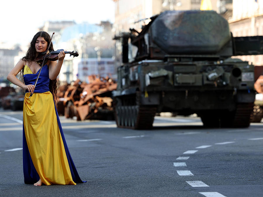 Kyiv (Ucraina). Una donna vestita con i colori della bandiera nazionale sfila davanti ai veicoli militari corazzati russi sequestrati dall’esercito ucraino, in un videoclip musicale realizzato in occasione della Festa dell’Indipendenza dall’Urss che ricorre oggi