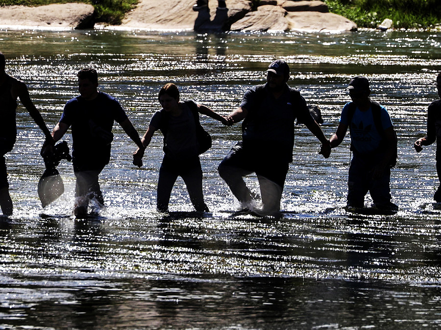 Eagle Pass (Texas). Migranti si tengono per mano mentre attraversano il Rio Grande. Il sindaco Rolando Salinas Jr. ha dichiarato uno “stato di disastro locale” dopo che migliaia di migranti hanno attraversato il confine.