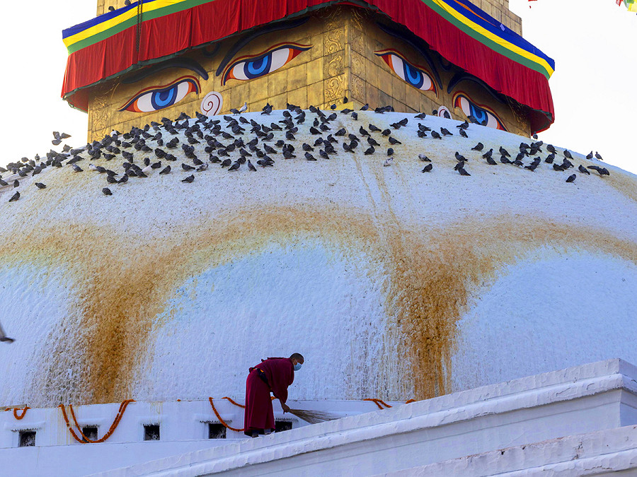Kathmandu (Nepal). Un monaco pulisce il Bauddhanath, uno dei pi&ugrave; grandi stupa (monumento) sferici del Paese e patrimonio dell&rsquo;Unesco. I pellegrini eseguono un rituale offrendo Syampur, stoffa per lo stupa, e Lungtar, bandiere di preghiera, per scacciare la sfortuna.