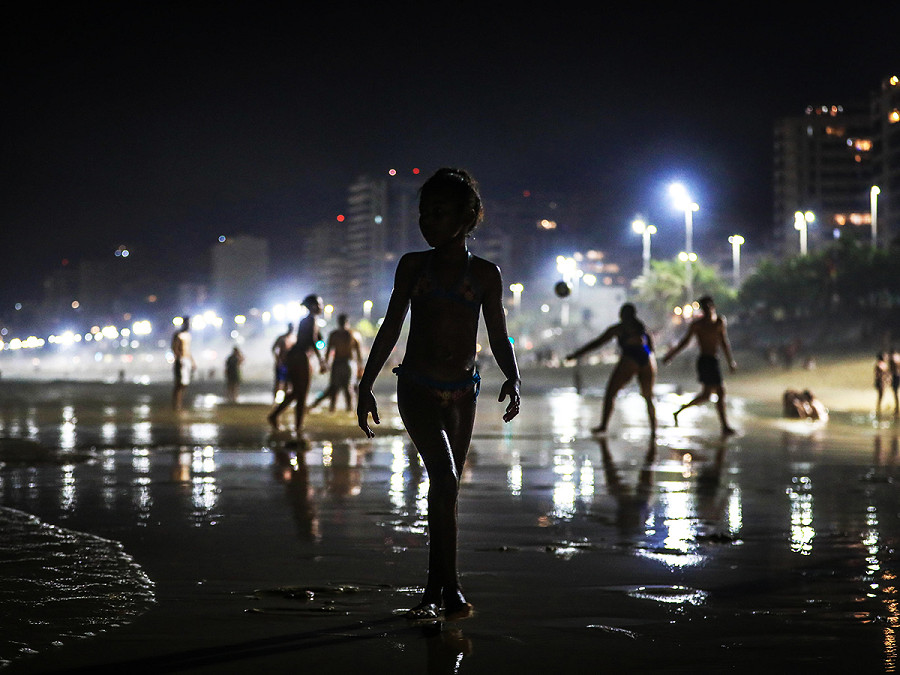 Rio De Janeiro (Brasile). Una bambina cammina sulla riva della spiaggia di Arpoador durante la notte. Secondo l’Istituto Nazionale di Meteorologia (Inmet), la citt&agrave; ha vissuto i giorni pi&ugrave; caldi dell’anno, con una temperatura massima di 40,6&ordm;C registrata dalla stazione di Marambaia.
