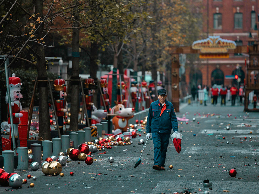 Shanghai (Cina). Un addetto alle pulizie cammina tra le decorazioni natalizie abbandonate per strada durante lo smontaggio di un mercatino di Natale. Le celebrazioni natalizie stanno diventando sempre pi&ugrave; popolari non solo tra gli stranieri ma anche tra i giovani cinesi. 