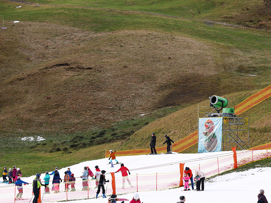 Oberstdorf (Germania). Adulti e bambini sciano su una pista circondata da montagne senza neve prima delle prove per il salto di apertura del torneo dei 4 trampolini di salto con gli sci Fis.