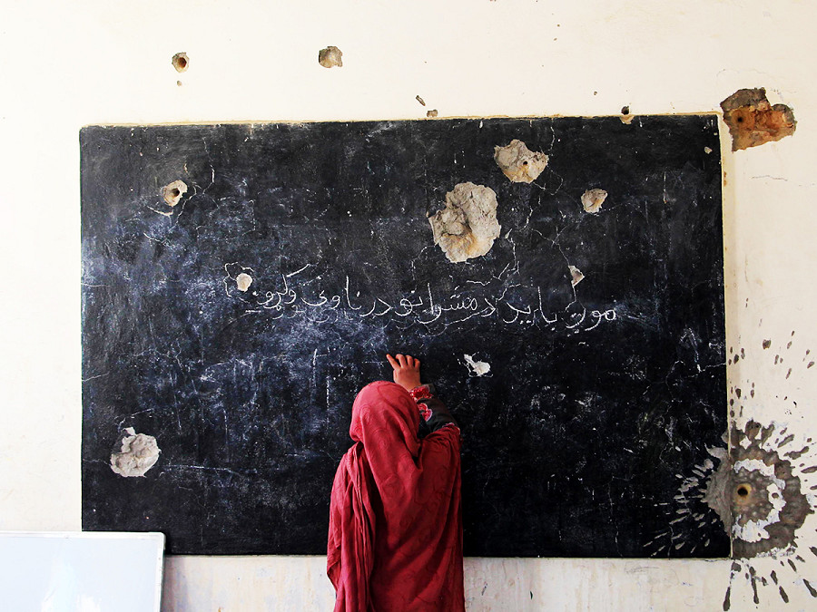 Kandahar (Afghanistan). Una studentessa afghana in una scuola danneggiata. Muri crivellati dai proiettili, finestre rotte e mancanza di servizi igienici e acqua sono all’ordine del giorno e spesso ostacolano l’istruzione dei ragazzi. Il Dipartimento dell’Istruzione di Kandahar ha riparato finora 81 istituti con aiuti esterni e sta lavorando su altri 31.