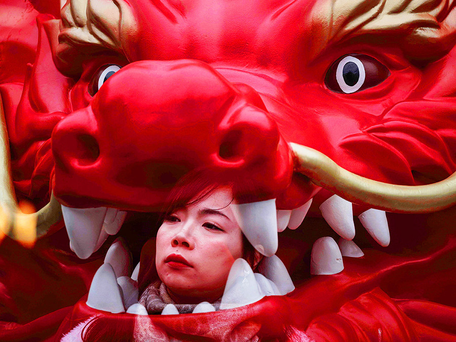 Shanghai (Cina). Una foto a doppia esposizione in-camera mostra una donna e una statua raffigurante un drago, installata per l’imminente Capodanno cinese, che segner&agrave; l’inizio dell’Anno del Drago. 