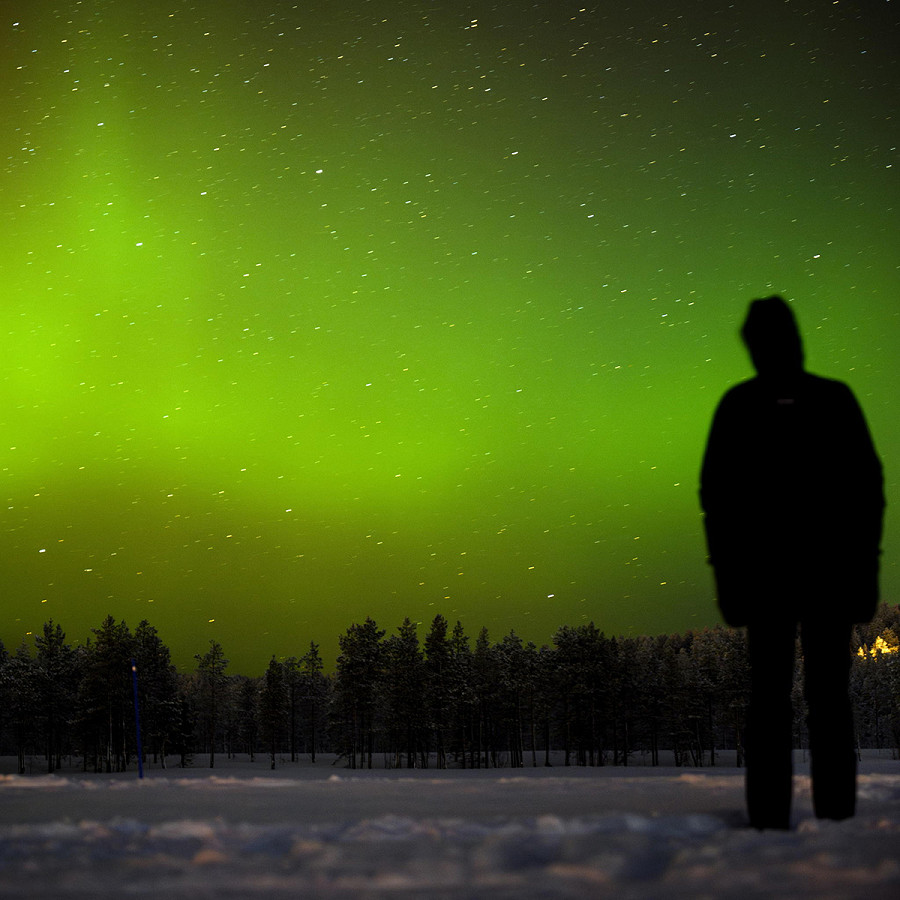 Akaslompolo (Finlandia). Una persona osserva l’aurora boreale che illumina il cielo sopra il villaggio a Kolari, oltre il Circolo Polare Artico. 