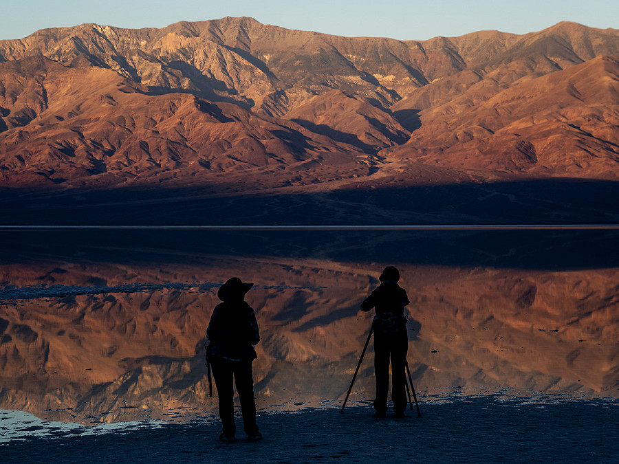 Due persone osservano il lago Manly nella Death Valley, il luogo pi&ugrave; secco d&rsquo;America. Grazie alle piogge da record che hanno inondato la California negli ultimi 6 mesi, si &egrave; riformato sul fondo del bacino di Badwater. Il National Park Service, per&ograve;, ha gi&agrave; interdetto la navigazione: &ldquo;troppo superficiale&rdquo;.