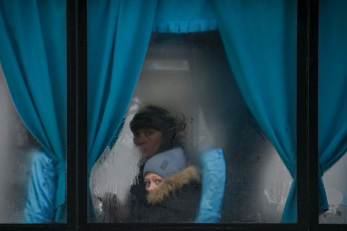 Una donna e un bambino guardano fuori dal finestrino di un autobus mentre lasciano Sjevjerodonec'k, il 24 febbraio 2022