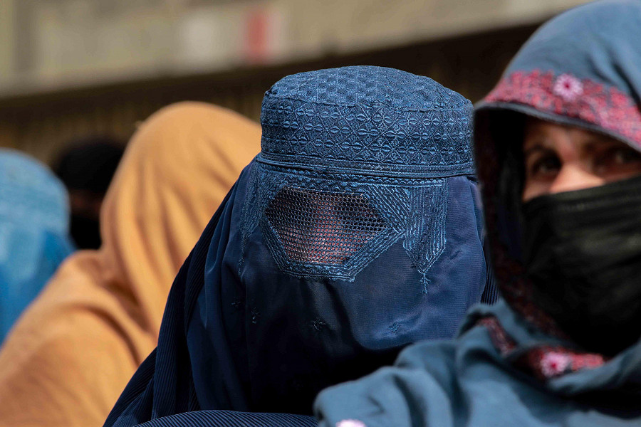 Una donna afghana che indossa il burqa cammina in una strada di Kabul. 