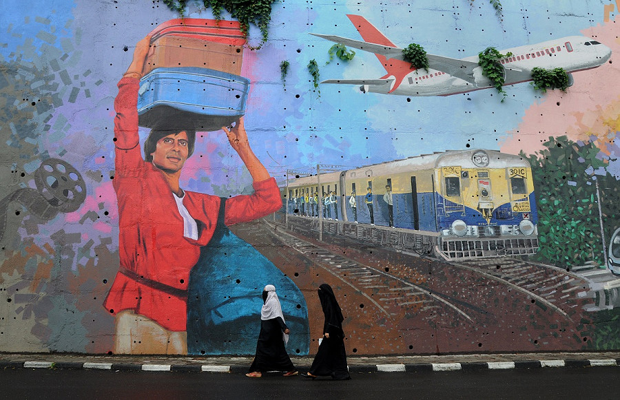 Due donne di Mumbai passano davanti a un murales dell'attore bollywoodiano Amitabh Bachchan