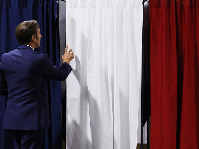 Il presidente francese Emmanuel Macron entra nella cabina elettorale per votare alle elezioni parlamentari francesi in un seggio a Le Touquet, nel nord della Francia, il 12 giugno 2022.
