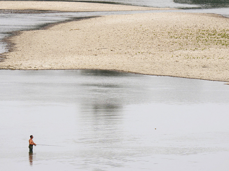 La gente pesca nei pressi di una centrale idroelettrica a Isola Serafini, sul fiume Po a San Nazzaro. 15 giugno 2022. 