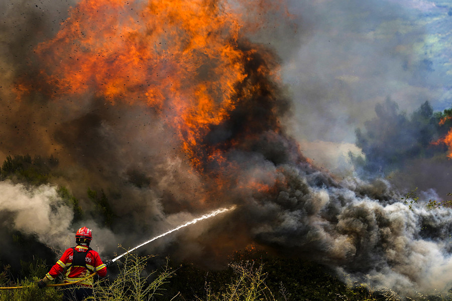 Un vigile del fuoco combatte le fiamme che circondano il villaggio di Ancede durante un incendio nel comune di Baiao, nel nord del Portogallo, il 15 luglio 2022.