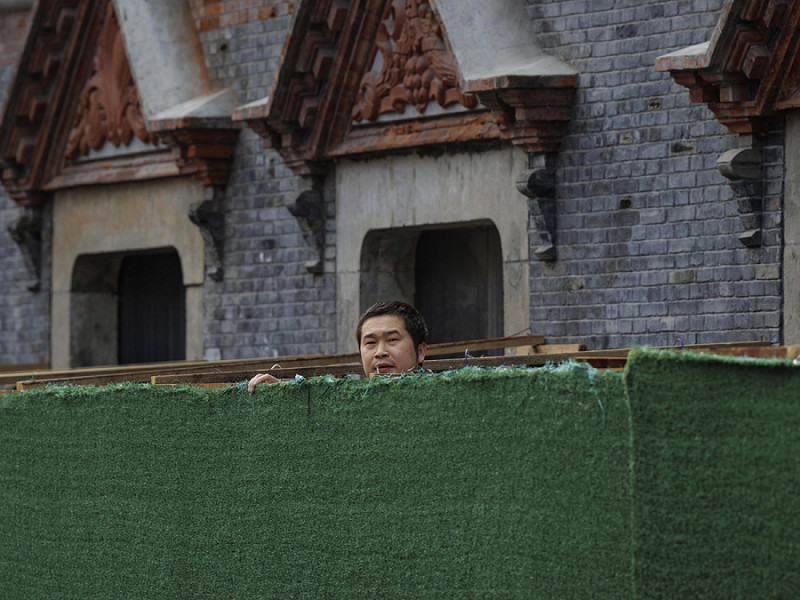 Un uomo a Shangai guarda la strada oltre la barriera di quarantena