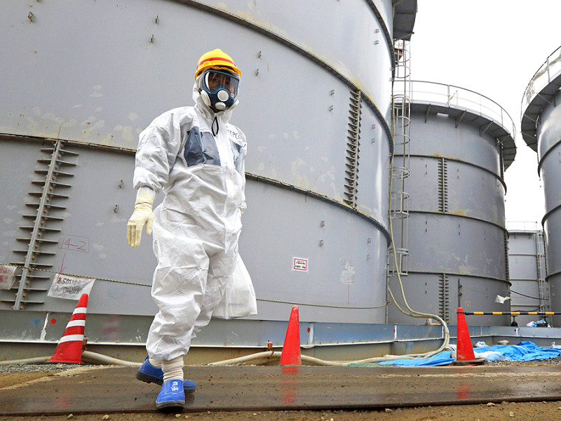 Un dipendente della Tokyo Electric Power Co. davanti ai serbatoi di stoccaggio dell'acqua radioattiva nella centrale nucleare di Fukushima nel 2013