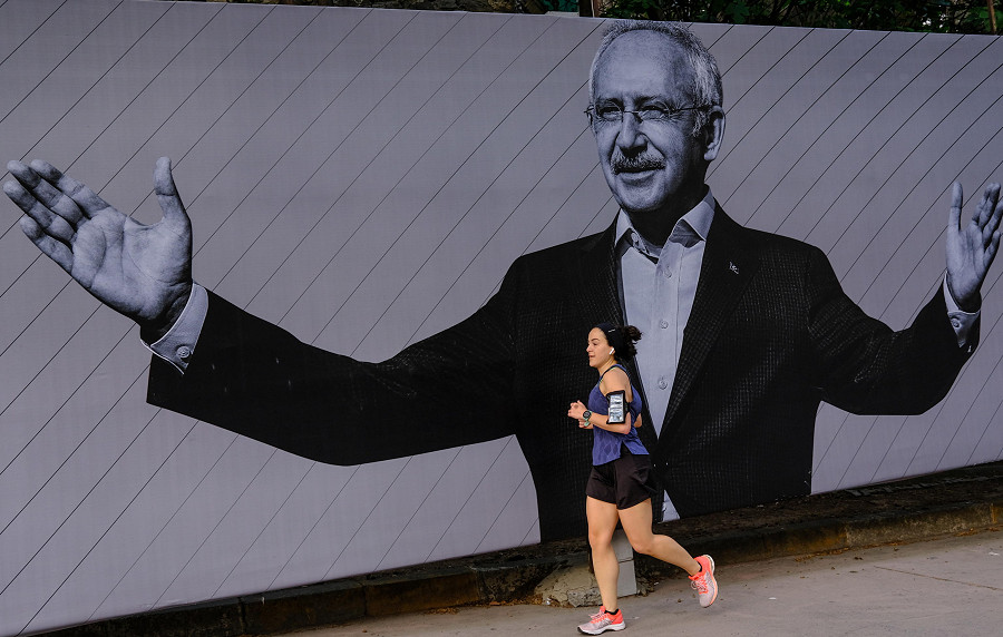 A woman runs in front of the picture of Turkish presidential candidate Kemal Kilicdaroglu