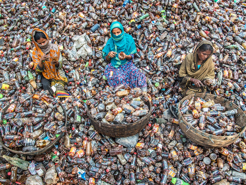 Barishal (Bangladesh). 3 donne raccolgono alcune bottiglie di plastica da inserire nelle ceste: quelle selezionate saranno riciclate per produrne di nuove. La foto è stata scattata per la Giornata mondiale dell'ambiente. 