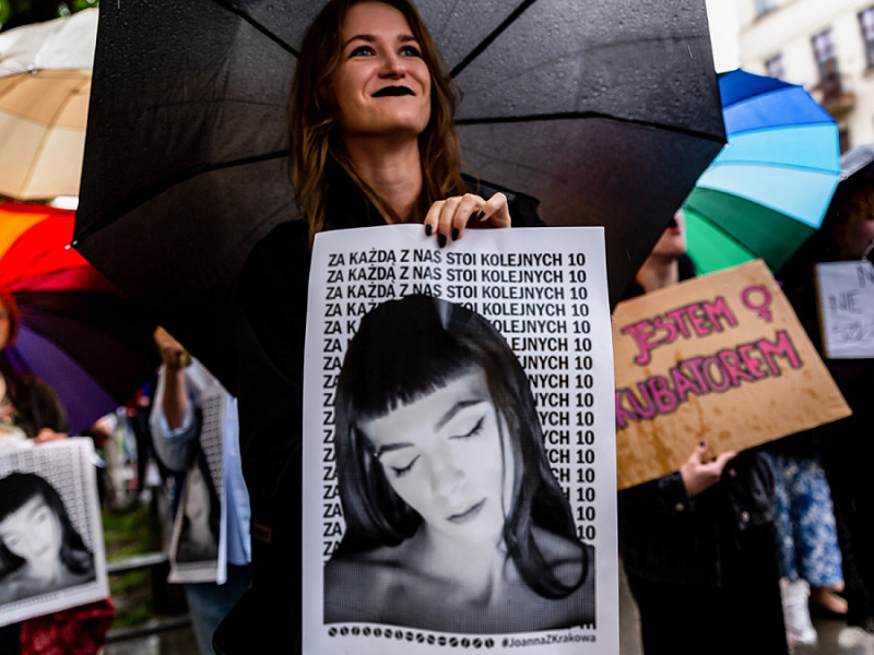Una manifestante mentre tiene un cartello raffigurante il volto di Joanna