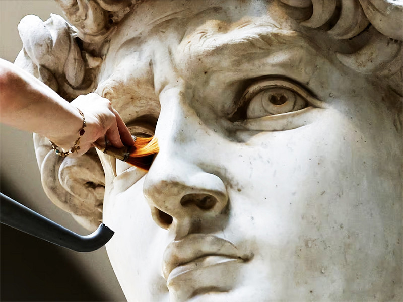 Firenze (Italia). La restauratrice Eleonora Pucci pulisce la statua del David di Michelangelo da polvere e detriti utilizzando un aspiratore museale e un pennello in fibra sintetica alla Galleria dell'Accademia di Firenze. 